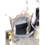 A cast metal fire grate, ornate brass fire screen and utensils