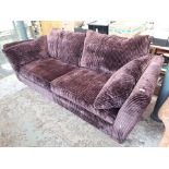 A purple coloured velour three seater sofa