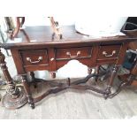 A reproduction three drawer lowboy with cross frame stretcher.