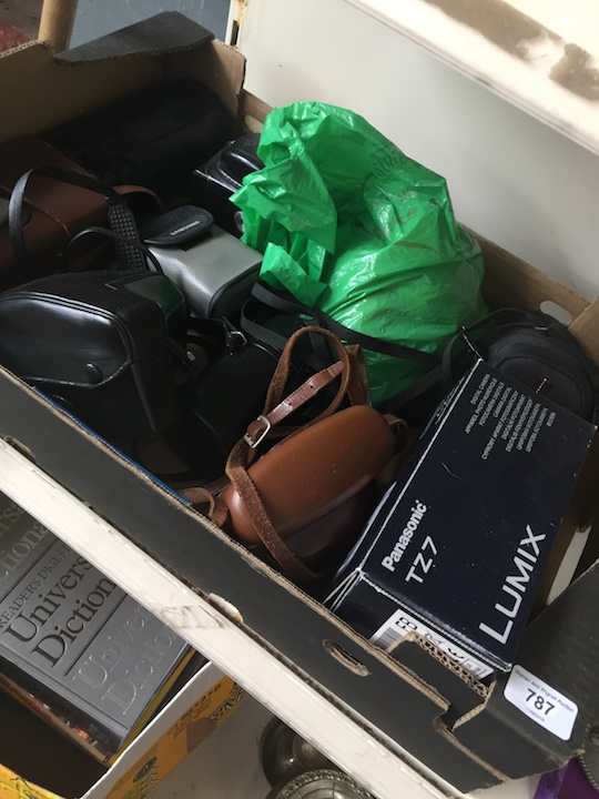 A box of various cameras, lenses and accessories.