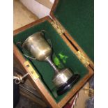 A small silver trophy in a wooden box