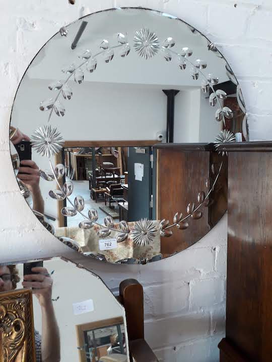 A round bevelled mirror and another vintage mirror with painted decoration.