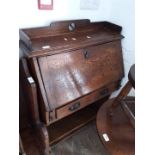 An oak bureau with Arts and Crafts style cut out.