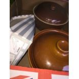 Two brown casserole dishes and a box of cutlery