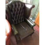 A Chesterfield green leather wing back armchair.