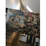 A wall hanging tapestry depicting a Classical scene with man playing flute, boy and goat.