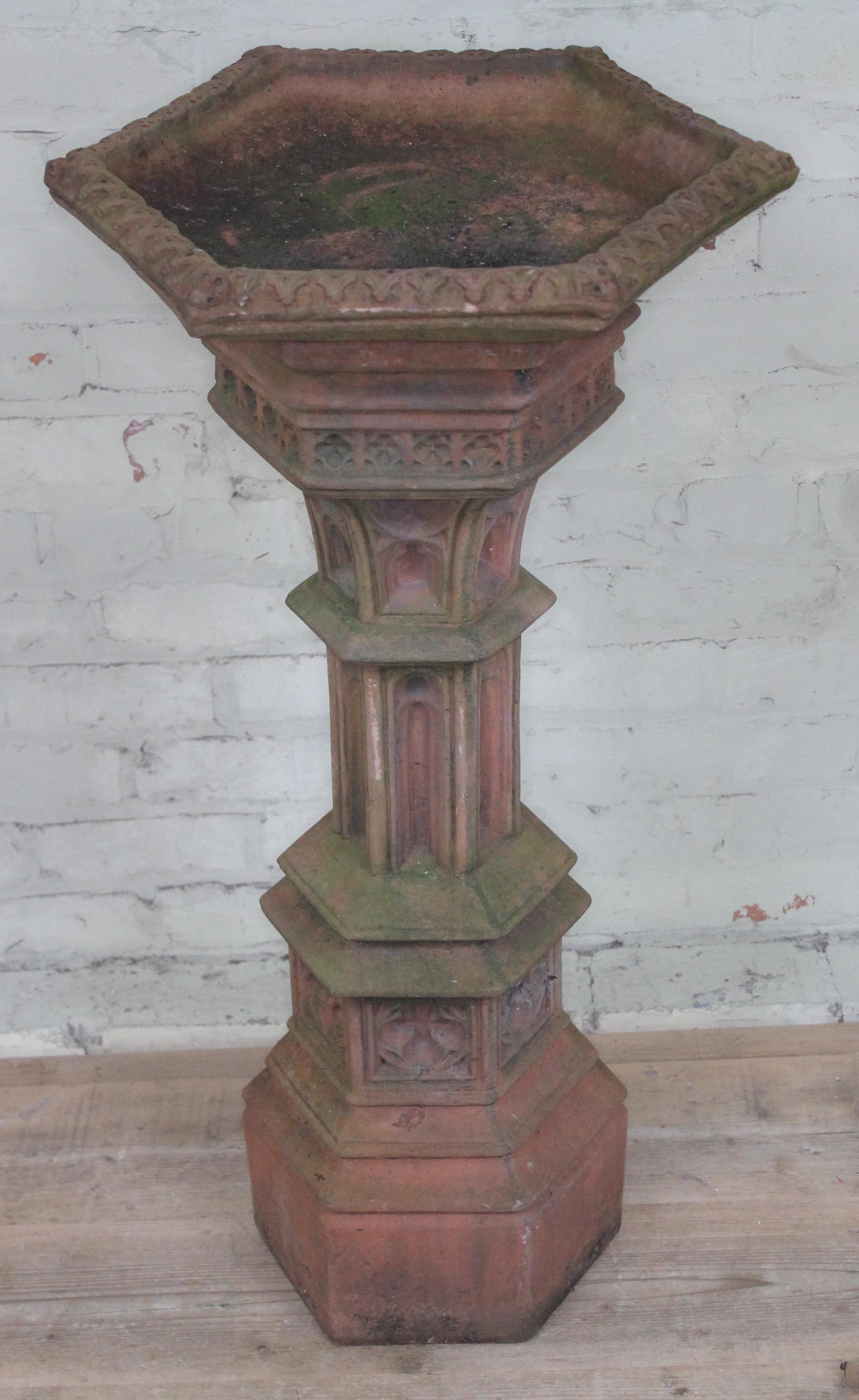 A terracotta coloured concrete bird bath of Gothic hexagonal column form, height 99cm.