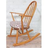 An Ercol blonde elm and beech Windsor rocking chair with spindle back and floral upholstered seat,