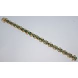 An 18ct gold diamond and emerald bracelet featuring 68 round brilliant cut diamonds and 65 round cut