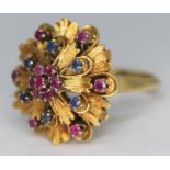 A sapphire and ruby cluster cocktail ring, the flower head diam. 20mm, band marked '750', gross