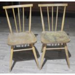 A pair of Ercol light elm and beech spindle back chairs.