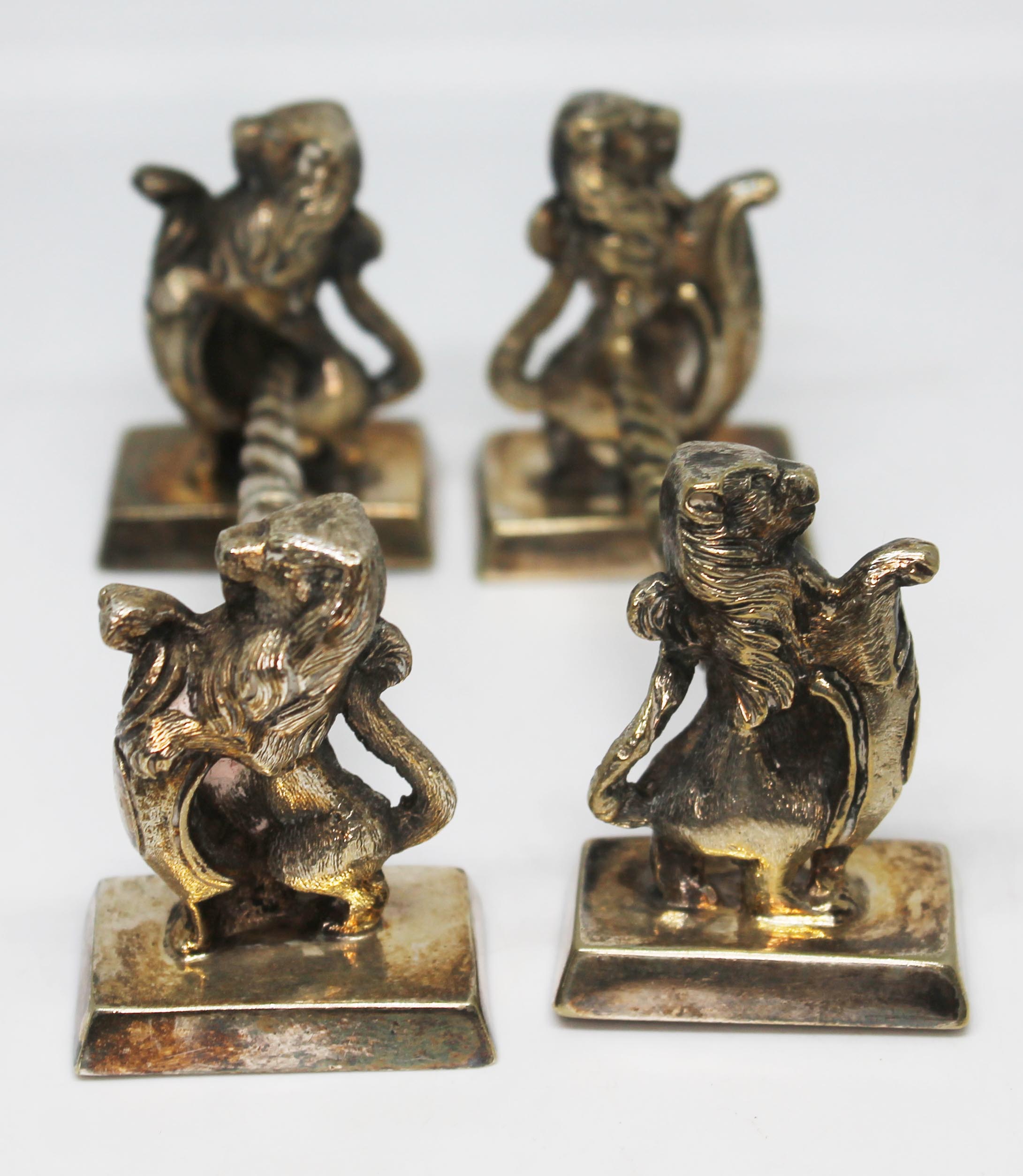 A pair of silver plated knife rests in the form of lions with shields, length 10cm.