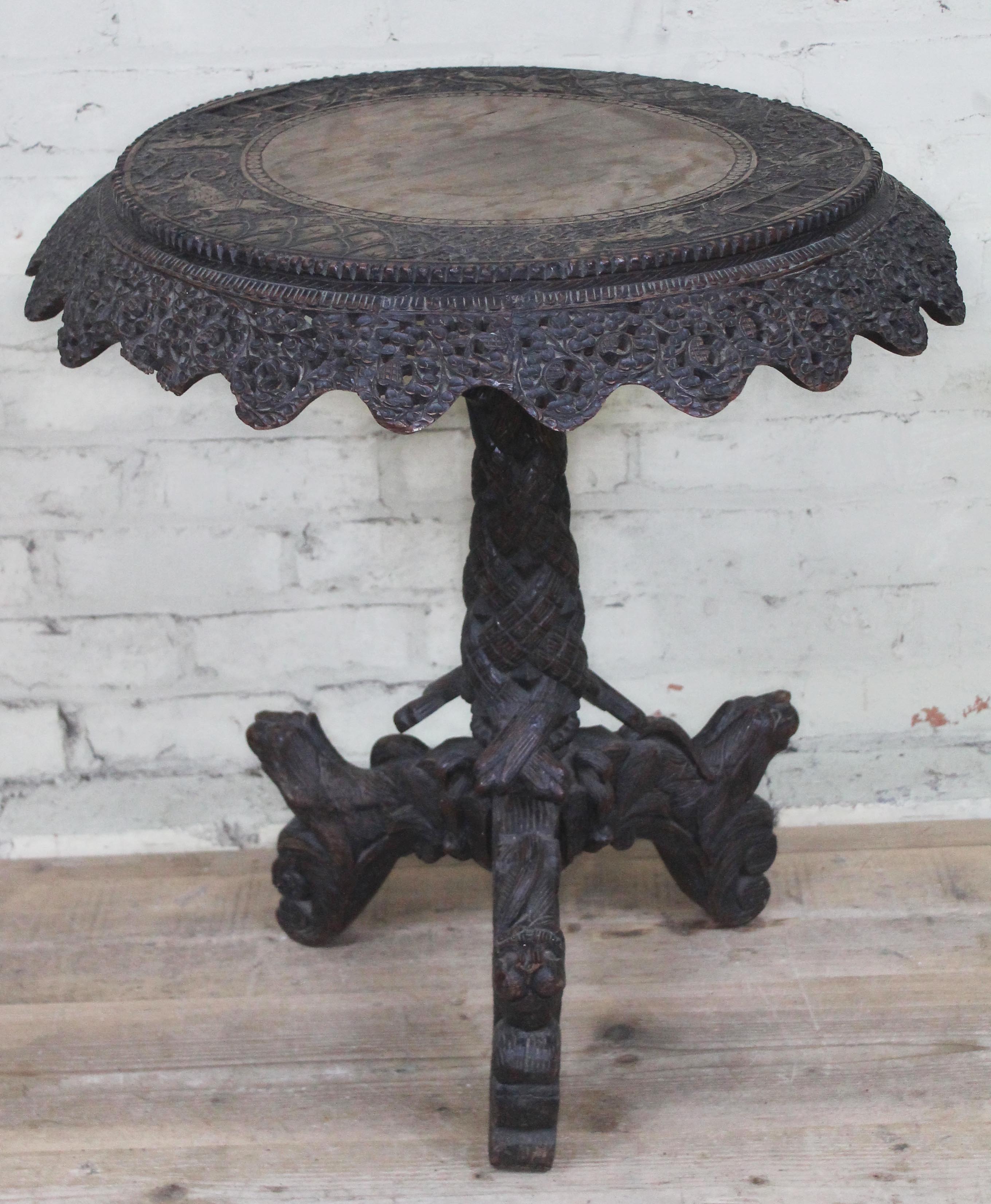 A 19th century Anglo-Indian rosewood tripod table with flip top and carved profusely with hunting