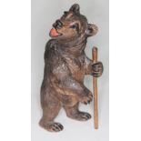 A Black Forest carved wooden bear holding a walking stick, height 14.5cm.