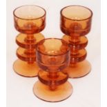 A group of three amber glass candle holders designed by Ronald Stennett-Wilson for Wedgwood,