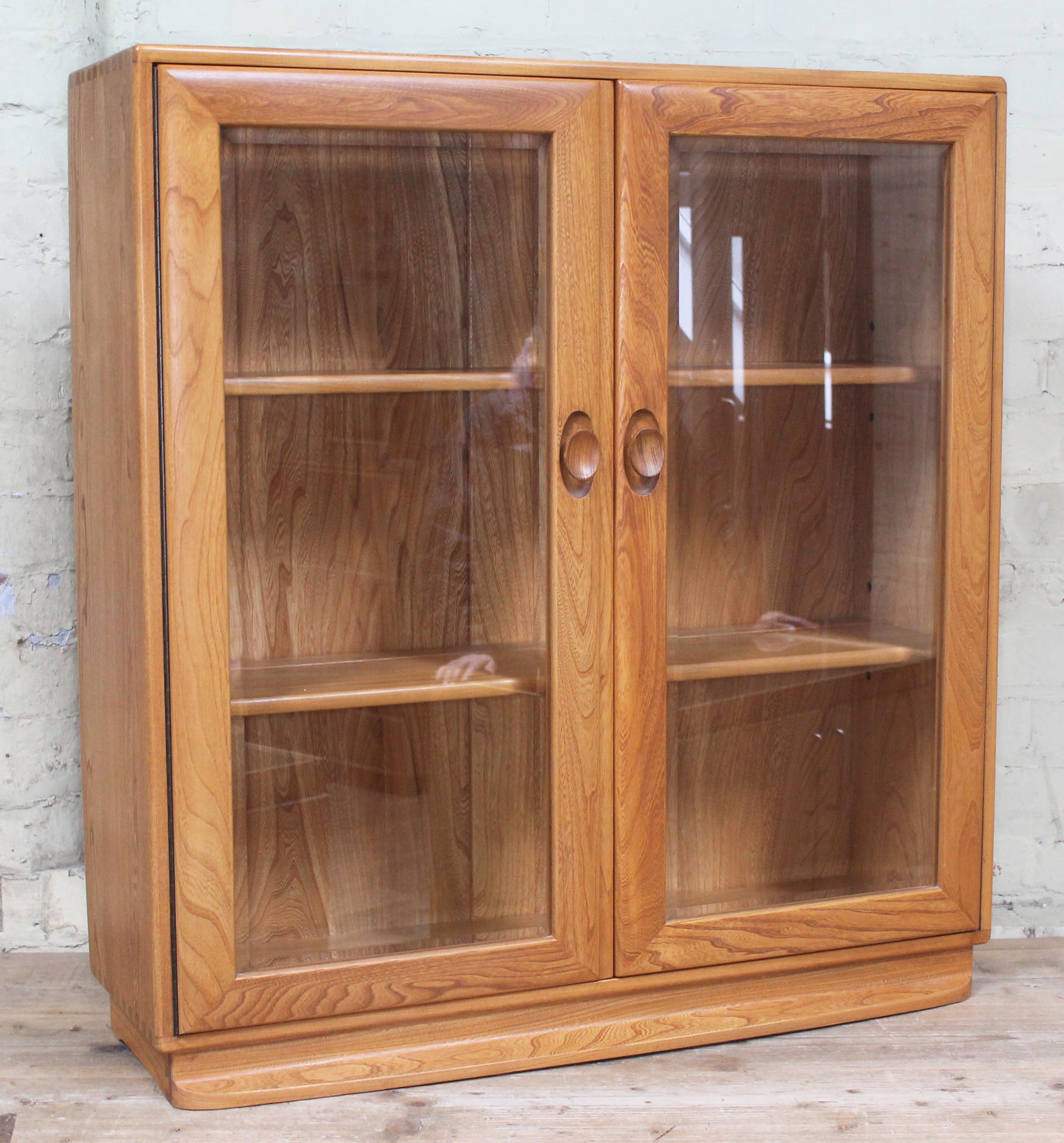 A elm and beech glazed bookcase with internal adjustable shelves and visible dovetail joints,