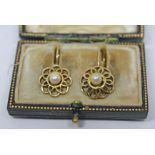 A pair of yellow metal earrings, each formed as an open work flower and set with a central