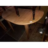 An oval extendable light wood dining table