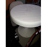A round white plastic table and an office swivel chair