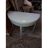 A painted flip top demi lune table on castors