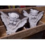 A pair of cherub oak mounted wall plaques