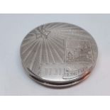 A silver compact engraved with scene depicting Bethlehem, marked 'LG 833' to back, diam. 58mm.