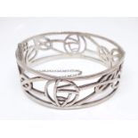 A vintage silver bangle, the pierced stylised flower design in the style of Charles Mackintosh,