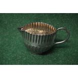 Small silver cream jug having crimped decorated top with embossed decoration of leaves,