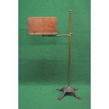 Oak book stand supported on adjustable tubular brass column leading to a decorative iron base with