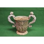 Lead urn in the form of a two handled goblet having cherub formed scrolled handles,