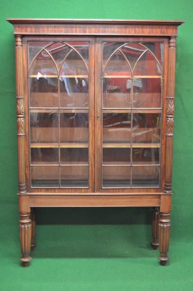 Mahogany glazed bookcase having moulded cornice over reeded columns and two glazed doors opening to