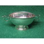 Silver two handled wine porringer having two hoop handles, standing on a circular footed base,