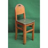 Oak Art Deco style childs high chair having solid back with pierced carrying handle supported on