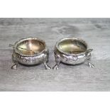 Pair of silver plated open salt cellars raised on three hoof feet, engraved floral decoration,