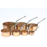 Seven Copper saucepans with Steel handles, in descending sizes and not silvered to the interiors,