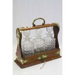 Oak cased three bottle Tantalus with hobnail cut glass Decanters, Brass fittings and a key