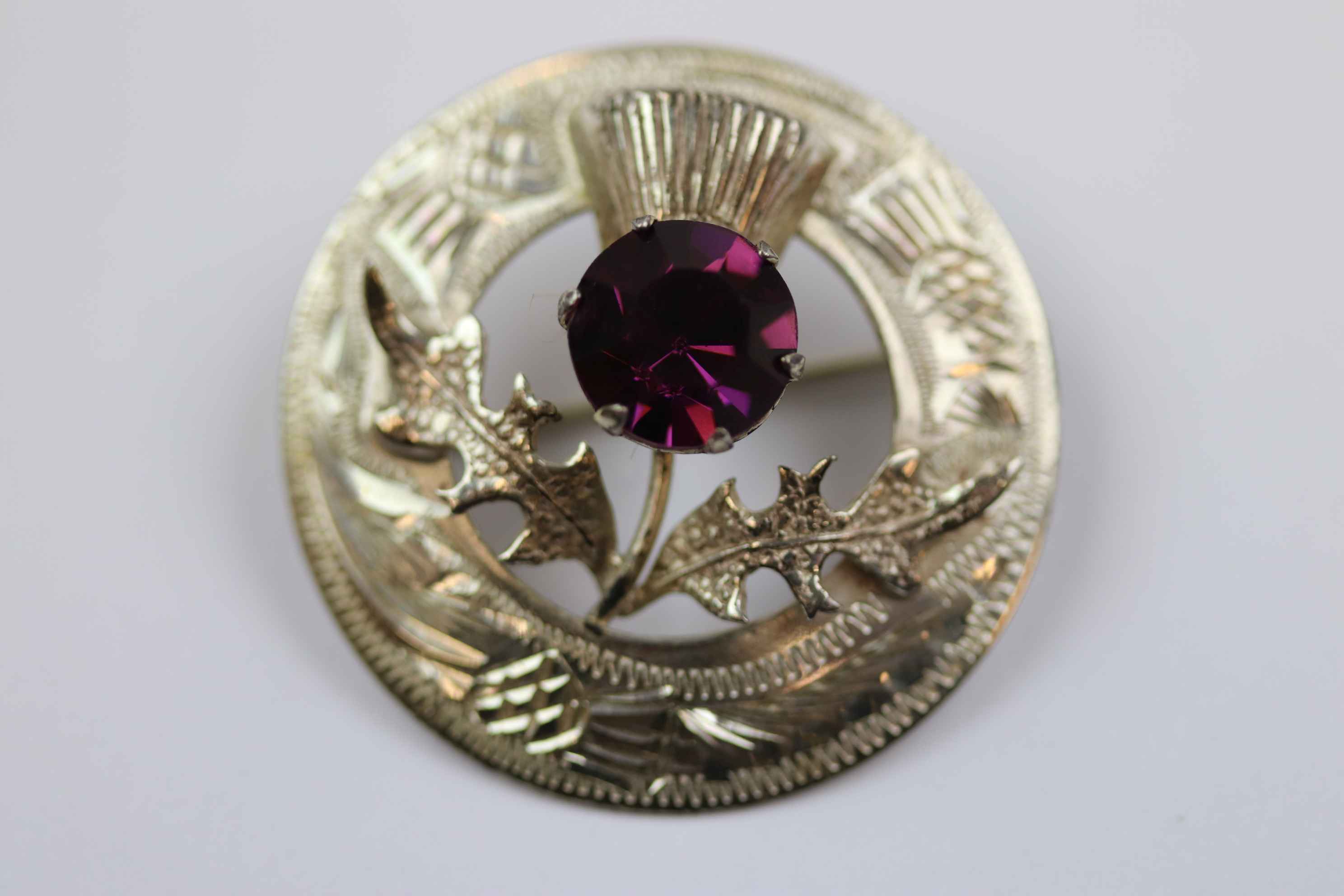 Mid twentieth century Scottish silver paste set thistle brooch, purple paste stone forming the