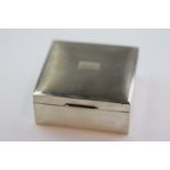 Silver cigarette box of square form, engine turned decoration to hinged lid, black rectangular