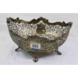 Pierced silver oval bowl raised on four feet, pierced foliate scroll decoration with two blank