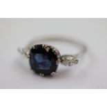 Sapphire and diamond three stone platinum ring, the central cushion shaped mixed cut royal blue