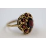 Garnet 9ct yellow gold cluster ring, the central oval mixed cut garnet measuring approximately 9mm x