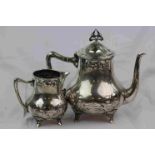 Early 20th century Art Nouveau EPNS teapot and milk jug each raised on four feet, sinuous floral and