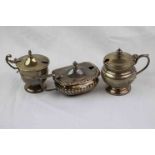 Three unassociated silver mustard pots/ salt cellars, comprising Edwardian example with gadrooning