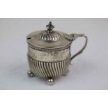 Victorian silver mustard pot with hinged lid raised on four ball feet, gadrooning to lower half