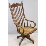 Late 19th / Early 20th century Oak High Back Swivel Office Chair with Cane Seat, the top rail carved