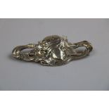 Silver Art Nouveau style brooch depicting a maiden with flowing hair and cascading stars, makers