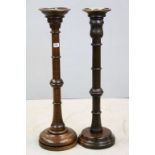 Two similar Oak Standard Candle Stands each set with a Brass Candle Holders and raised on turned