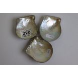 White metal mounted mother-of-pearl shell salt cellars, each with pearl to corner and raised on