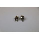 Pair of silver skull style stud earrings with ruby eyes
