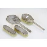 A hallmarked silver four piece dressing table set to include three brushes and a mirror.